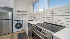 Una cucina moderna con frigorifero in acciaio inossidabile, lavatrice, lavastoviglie e piano cottura con pannello di controllo digitale.