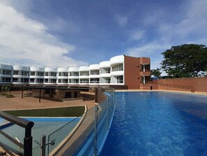Una piscina al aire libre, sombrillas, sillones reclinables de piscina