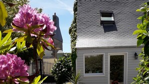 A white house with a brick roof, a gravel driveway, and potted plants. - 2-person gîte 7 minutes from surf spots, beaches and hiking trails. (PLONEOUR LANVERN)