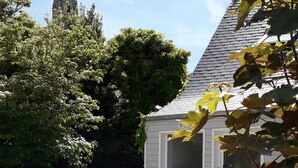 A small white building with a sloped roof, surrounded by gravel and potted plants. - 2-person gîte 7 minutes from surf spots, beaches and hiking trails. (PLONEOUR LANVERN)