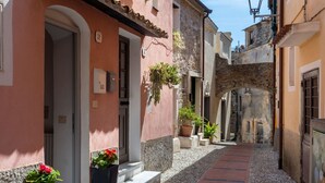 A narrow cobblestone street flanked by historic buildings with arched doorways and potted plants. - Beautiful  villa for 6 guests with WIFI, TV, terrace, pets allowed and panoramic view (Cipressa)