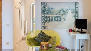 A modern living room with a yellow chair, a small table with a cup and a book, a painting on the wall, and a TV on a white table. - Beautiful  villa for 6 guests with WIFI, TV, terrace, pets allowed and panoramic view (Cipressa)