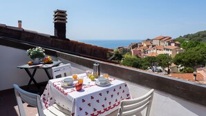 Un balcon avec une table préparée pour le petit-déjeuner, donnant sur une ville côtière.