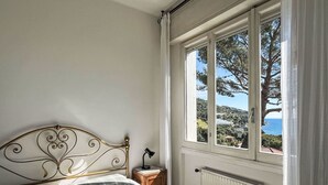 Une chambre à coucher avec un lit, une table de chevet et une fenêtre donnant sur un paysage côtier.