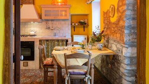 A cozy kitchen with a dining table set for two, a stone wall, and a hanging light fixture. - Lovely apartment for 3 people with WIFI and balcony (Dolcedo)