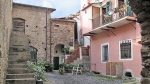 A courtyard with stone buildings, a staircase, and potted plants. - Lovely apartment for 3 people with WIFI and balcony (Dolcedo)