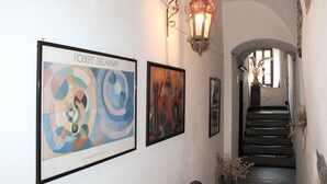 A hallway with two framed artworks, a wrought iron light fixture, and a staircase leading to an upper level. - Lovely apartment for 3 people with WIFI and balcony (Dolcedo)