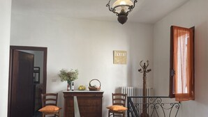 Um corredor com uma escrivaninha de madeira, duas cadeiras, um radiador e uma escada com grades de ferro forjado.
