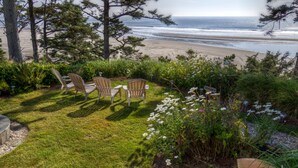 A patio with two Adirondack chairs overlooking a beach. - Tyee Lodge Oceanfront B&B (Newport)