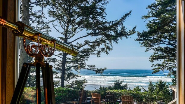 A telescope, chairs, and a view of the ocean through a window. - Tyee Lodge Oceanfront B&B (Newport)