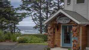 A lodge with a wooden exterior, a sign reading "Tyee Lodge B&B," and totem poles in front. - Tyee Lodge Oceanfront B&B (Newport)