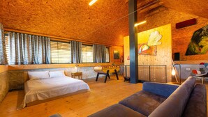 Ein gemütliches Zimmer mit einem Bett, einem Schlafsofa, einem kleinen Tisch und einem Bild an der Wand.
