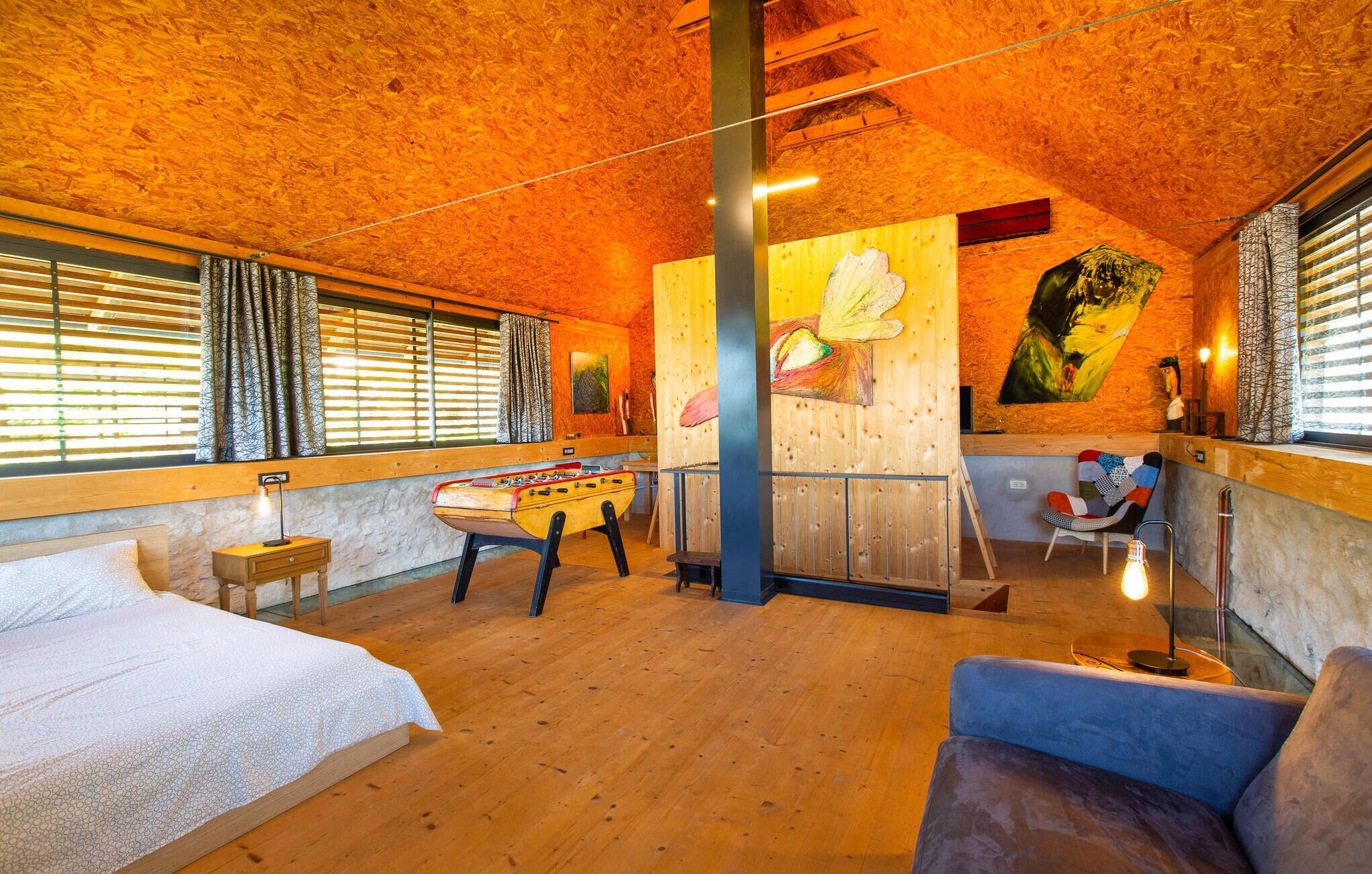Ein gemütliches Zimmer mit Holzwänden und Holzböden, einem Bett, einem Tischkicker und einem Stuhl.