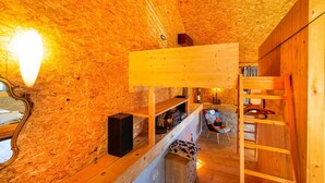 Ein gemütliches Holzinterieur mit einem Etagenbett, einem Spiegel und einem Regal mit Büchern und einem Lautsprecher.