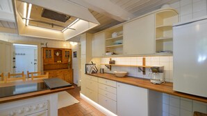Una cocina con armarios blancos, una encimera de madera, una cafetera y una estufa.