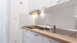 A modern kitchen with white cabinets, a stainless steel sink, and a wooden countertop. - Awesome apartment in Rukavac with WiFi (Rukavac)