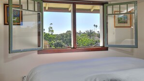 A bedroom with a large window, a bed, and two framed pictures on the wall. - Downtown Craftsman Bungalow (Santa Barbara)