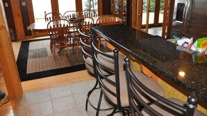 Una cocina con sillas de madera, encimera de granito y refrigerador.