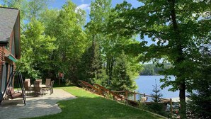 Una propiedad frente al lago con patio, mobiliario exterior y un columpio.