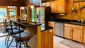 Una cocina moderna con armarios de madera, encimera negra y una barra con taburetes.