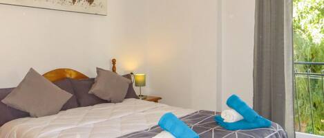 A neatly made bed with a patterned bedspread, two pillows, and two rolled towels on the bed.