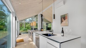 Una cocina moderna con una isla grande, estufa integrada y un ventanal con vistas a un jardín.