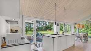Una cocina moderna con una isla grande, un comedor con asientos al aire libre y vistas a un jardín exuberante.