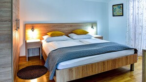 A bedroom with a wooden bed, two bedside tables with lamps, a dark rug, and a painting on the wall. - Stunning home in Smokovic (Smokovic)