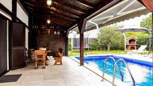 A covered outdoor area with a pool, wooden furniture, and a barbecue grill. - Stunning home in Smokovic (Smokovic)