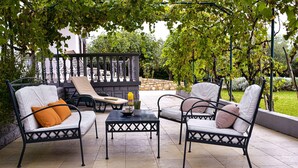 An outdoor patio with two white cushioned chairs, a small table, and a yellow bottle. - Stunning home in Smokovic (Smokovic)