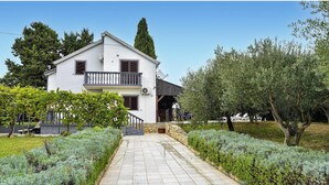A two-story building with a balcony, surrounded by well-maintained gardens and olive trees. - Stunning home in Smokovic (Smokovic)