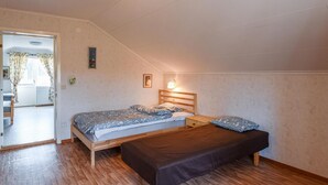 Un dormitorio con una cama de madera, una mesita de noche, una lámpara de pared y una puerta que da a un balcón.
