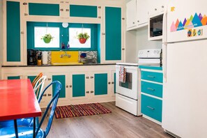 A kitchen with teal cabinetry, a red table, and a patterned rug. - Hot Tub Retreat Near Turner Falls (Davis)