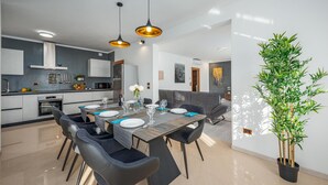 Un espace de salle à manger moderne avec une table en bois, des chaises noires et des luminaires suspendus.