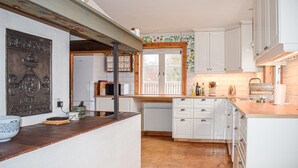 A kitchen with white cabinets, a wooden countertop, and a window with a view of trees. - Beautiful home in Lammhult with sauna (Lammhult)