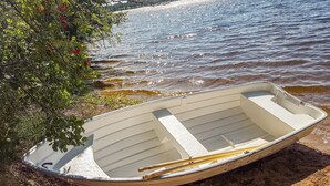 A small rowboat with a white interior, resting on a sandy shore next to a body of water. - Beautiful home in Lammhult with sauna (Lammhult)