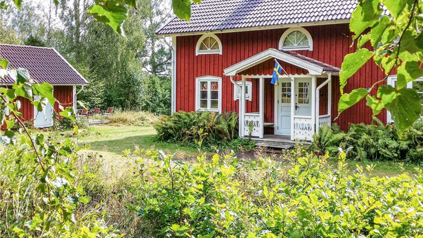 A red wooden house with a white porch and a flag. - Beautiful home in Lammhult with sauna (Lammhult)