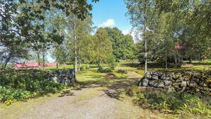 A gravel path leading through a rural landscape with stone walls and trees. - Beautiful home in Lammhult with sauna (Lammhult)