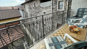 Un balcon avec une balustrade en fer forgé, une table sur laquelle se trouve un plateau de nourriture et une chaise.