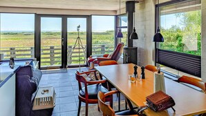 Een zithoek met een grote tafel en stoelen, een bank en een telescoop op een balkon met uitzicht op het landschap.