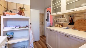 Een kleine keuken met witte kastjes, een aanrecht en diverse keukengerei.