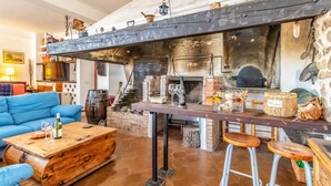 Una zona de bar rústica con chimenea de ladrillo, taburetes de madera y una barra.
