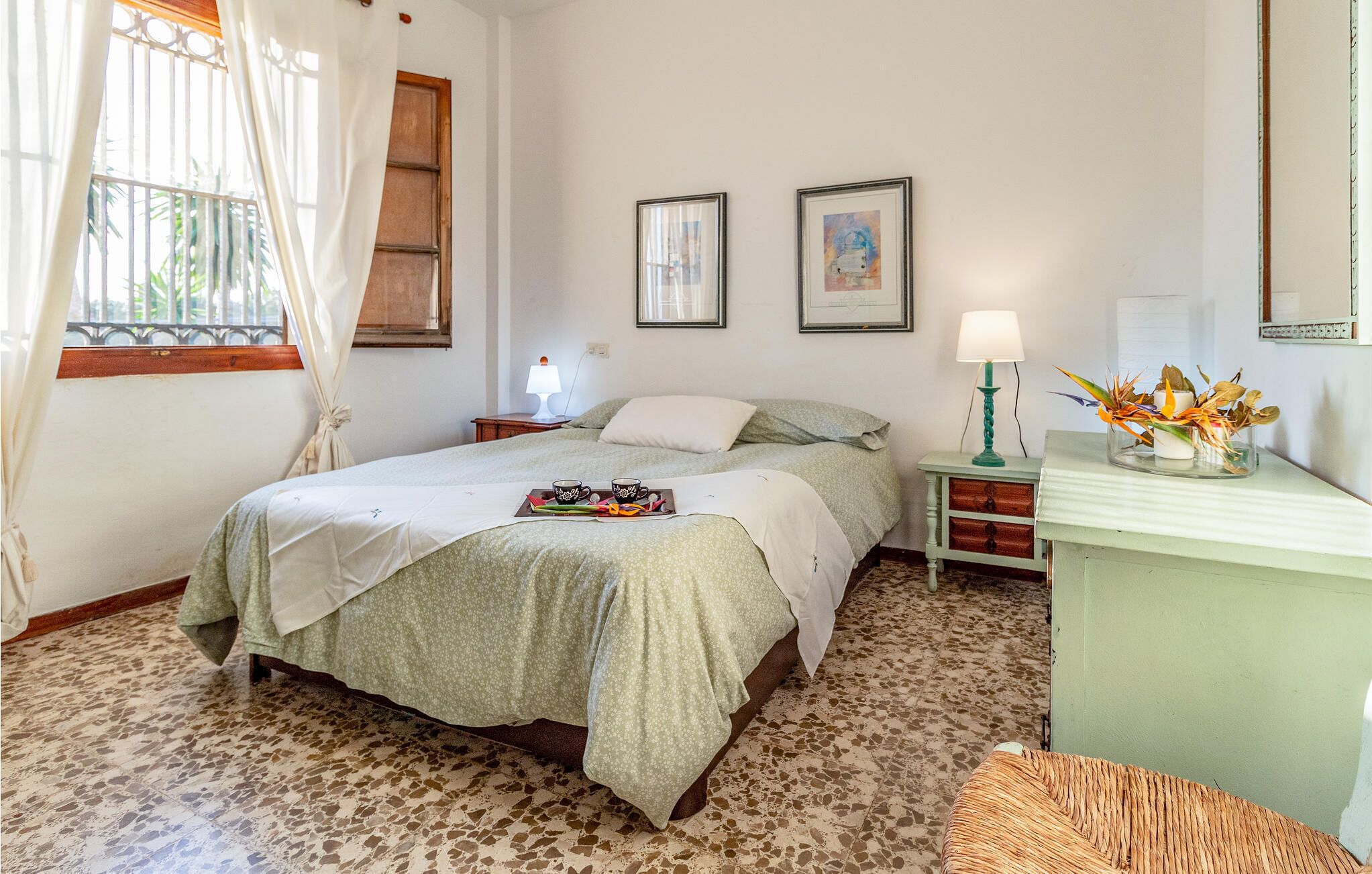 A bedroom with a bed, bedside tables, a lamp, and artwork on the wall.