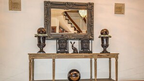 Um console de madeira com um espelho, dois vasos decorativos e uma estátua de Buda.