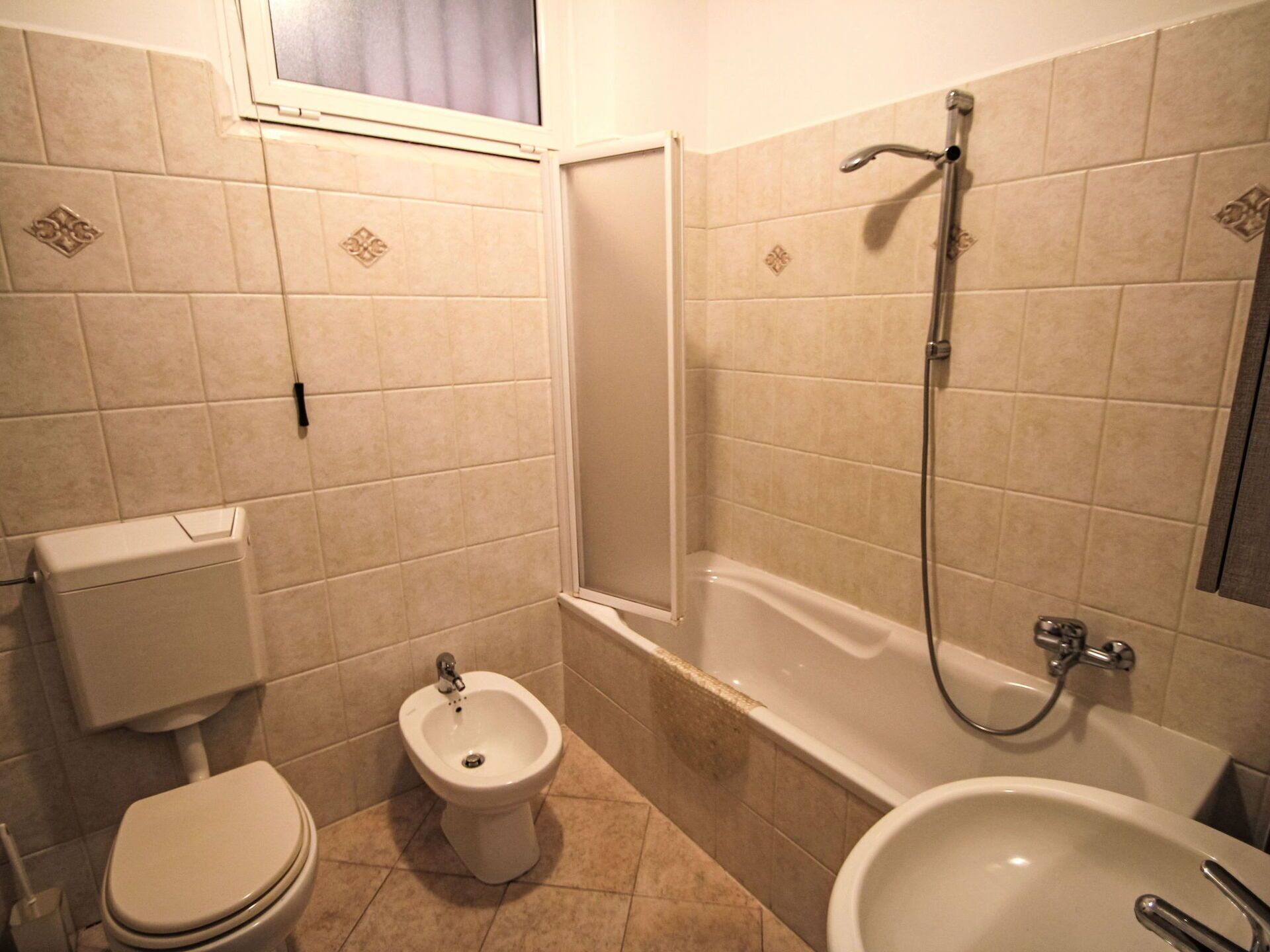 A bathroom with a toilet, bidet, bathtub, and sink.