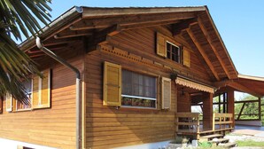 Une cabane en bois dotée d’un porche, de grandes fenêtres et d’un toit en pente.