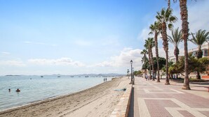 A beach with a paved walkway lined with palm trees, leading to the sea. - Beach front home in Los Alcázares (Los Alcázares)