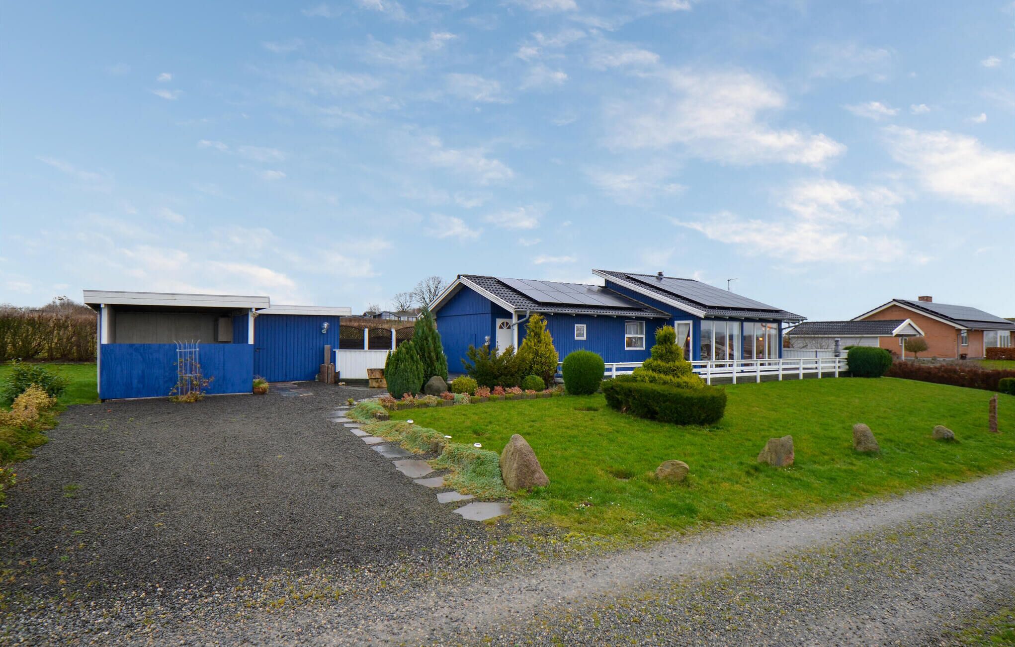 A residential area with houses, a gravel driveway, and a grassy lawn.