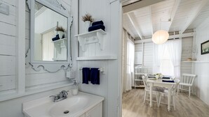 A white wooden interior with a sink, mirror, and white dining table with chairs. - Quintessential seaside cottage in beautiful Pott's Point (Harpswell)