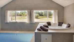 Une salle de bain moderne avec une baignoire, une douche et une fenêtre avec des rideaux.